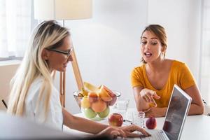 Professional nutritionist meeting a patient in the office. young smiling female nutritionist in the consultation room. Nutritionist desk with healthy fruit and measuring tape. photo