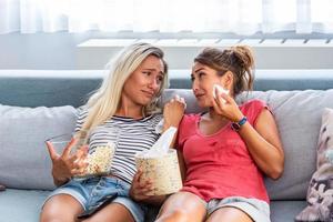 Sad girls watching a movie Crying for a touching movie. two best friends watch sad movie at home in bed crying touching. photo