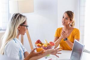 médico nutricionista, dietista y paciente femenino en consulta en el consultorio. hacer un plan de dieta. mujer joven visitando a nutricionista en la clínica de pérdida de peso foto