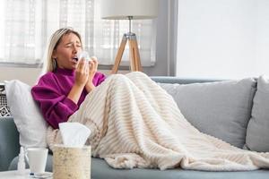 Sick Woman.Flu.Woman Caught Cold. Sneezing into Tissue. Headache. Virus .Medicines. Young Woman Infected With Cold Blowing Her Nose In Handkerchief. Sick woman with a headache sitting on a sofa photo