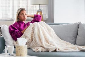 Sick Woman.Flu.Woman Caught Cold. Sneezing into Tissue. Headache. Virus .Medicines. Young Woman Infected With Cold Blowing Her Nose In Handkerchief. Sick woman with a headache sitting on a sofa photo