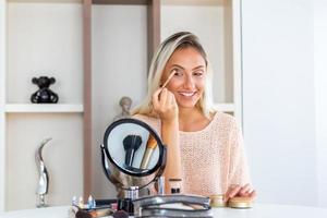 Eye makeup woman applying eyeshadow powder. Young beautiful woman making make-up near mirror,sitting at the desk photo