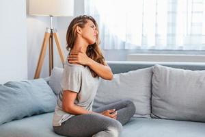 Pain in the shoulder. Upper arm pain, People with body-muscles problem, Healthcare And Medicine concept. Attractive woman sitting on the bed and holding painful shoulder with another hand. photo