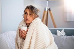 resfriado y gripe. retrato de una mujer enferma resfriada, sintiéndose enferma y estornudando en una toallita de papel. primer plano de una hermosa niña malsana cubierta de manta limpiándose la nariz. concepto de salud. foto