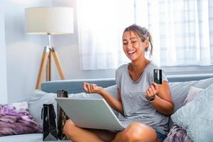 mujer joven con tarjeta de crédito y usando computadora portátil. concepto de compras en línea. mujer feliz haciendo compras en línea en casa foto