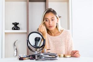 Eye makeup woman applying eyeshadow powder. Young beautiful woman making make-up near mirror,sitting at the desk photo