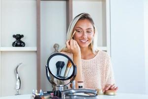 Eye makeup woman applying eyeshadow powder. Young beautiful woman making make-up near mirror,sitting at the desk photo
