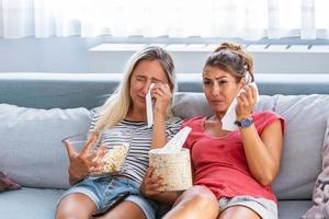 Sad girls watching a movie Crying for a touching movie. two best friends watch sad movie at home in bed crying touching. photo