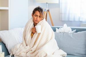 Cold And Flu. Portrait Of Ill Woman Caught Cold, Feeling Sick And Sneezing In Paper Wipe. Closeup Of Beautiful Unhealthy Girl Covered In Blanket Wiping Nose. Healthcare Concept. photo