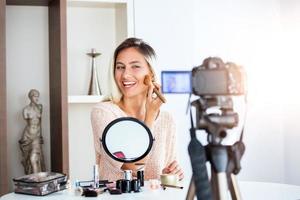 joven hermosa mujer rubia vlogger de belleza profesional o blogger grabando tutorial de maquillaje para compartir en las redes sociales foto