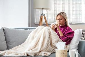 Cold And Flu. Portrait Of Ill Woman Caught Cold, Feeling Sick And Sneezing In Paper Wipe. Closeup Of Beautiful Unhealthy Girl Covered In Blanket Wiping Nose. Coronavirus, covid-19 photo