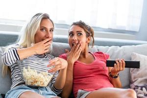 Portrait of a happy girlfriends eating popcorn and watching tv at home. Girls night, entertainment and junk food concept watching tv and movies photo