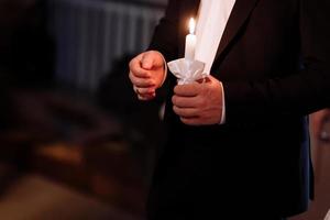 pareja en la iglesia. el novio sostiene velas brillantes durante la ceremonia en la iglesia. manos de recién casados con velas en la iglesia. detalles religiosos de la iglesia. los recién casados se juran amor para siempre. foto