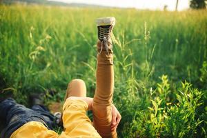 woman and man having fun outdoors. Loving hipster couple walking in the field, kissing and holding hands, hugging, lying in the grass and lifting their legs up in the summer at sunset. valentines day photo