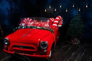 tro red car with led red inscription merry christmas on it. big christmas lollipops in the car in studio background photo