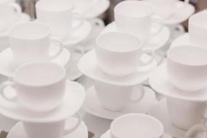 muchas filas de tazas blancas puras con platos para tomar café o té. foto de alta calidad