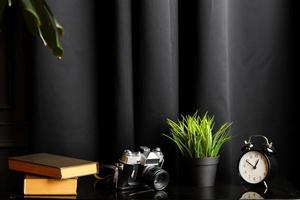 Office creative desk with camera, clock, books and houseplant on black table. High quality photo