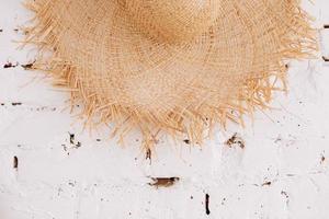 a straw hat on a background of a white brick wall with copy space. Travel concept photo