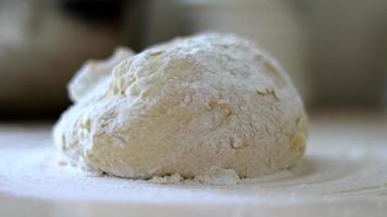 The chef sprinkles flour on the pastry. A round piece of dough lies in flour on the kitchen table. Cooking, bakery. The baker kneads the dough, sprinkles flour on the table while kneading the dough. video