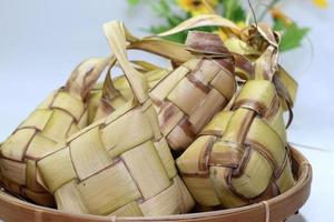 Ketupat is traditional indonesian food, woven coconut leaves filled with rice and eaten with papaya vegetables, , served on Eid al-Fitr or Eid al-Adha photo