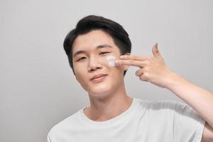 Young man with moisturizer on the face photo