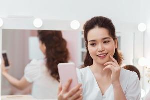 beauty asian woman makeup and take selfie in mirror photo