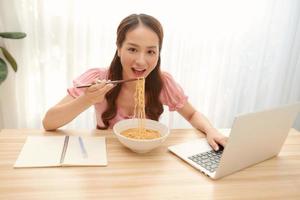 empresaria asiática tiene que comer fideos mientras trabaja foto