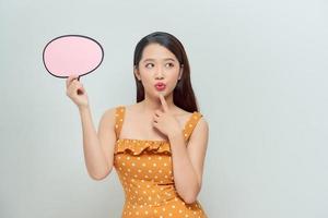 Happy woman holding blank speech bubble over bright background photo