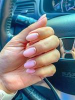 female hands demonstrating fresh manicure hold the steering wheel of a honda car photo