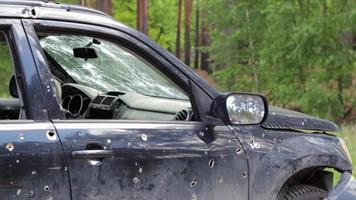 kogel gat in een auto deur. verlaten auto met kogel gaten. een vernietigd voertuig in een oorlog zone in Oekraïne. beschadigd burger auto. de auto was beschadigd door granaatscherven net zo een resultaat van vijandelijkheden. video