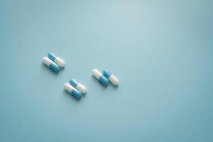 Pairs of white-blue antibiotic capsule pills on blue background. Antibiotic drug. Prescription drug. Pharmacology and recommended dose concept. Pharmaceutical industry. Medical and healthcare concept. photo