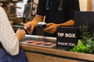 Asia woman use cashless wifi paywave scan on card reader in coffee shop. photo