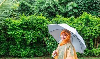 Asian boy puts on a raincoat and opens an umbrella on a rainy day. photo