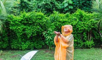 Asian boy wearing orange raincoat is happy and having fun in the rain on a rainy day. photo