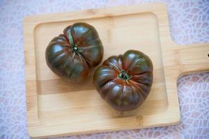 Two organic tomatoes on a wooden cutting board photo