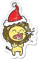 distressed sticker cartoon of a roaring lion wearing santa hat vector