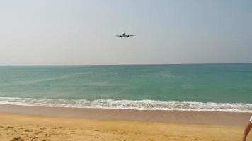 un avion de passagers arrive sur l'île de phuket, atterrissant au-dessus de la mer, sur la plage avec des touristes. concept de tourisme et de voyage. frontières fermées video