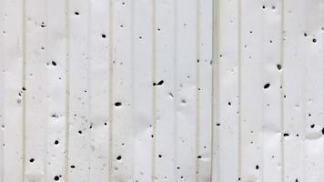 avvicinamento di un' metallo recinto con proiettile fori nel il luce del sole all'aperto. il concetto di il conseguenze di il guerra nel Ucraina. proiettile fori nel il recinto di un' Residenziale costruzione. panorami. video