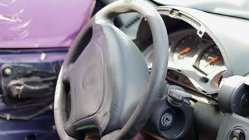 primer plano del volante de un coche después de un accidente. las bolsas de aire del conductor no se desplegaron. enfoque suave. parabrisas roto con volante. interior del vehiculo salpicadero y volante negros. video