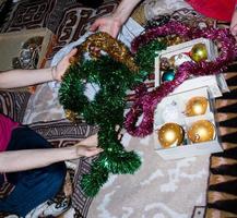 Two women are choosing Christmas decorations for the home tree. Womans hands are holding Christmas toys and garlands. photo