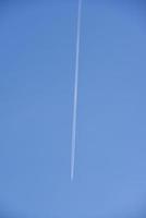 The contrail of an airplane in the blue sky. The flight of a passenger plane. photo