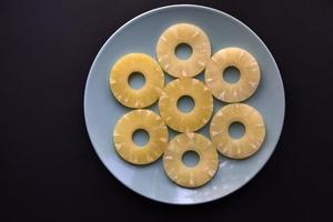 Delicious fresh pineapple rings on a plate on a black background. Delicious breakfast of pineapple rings. photo