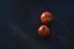 Delicious juicy tomatoes on a black background. Several tomato fruits in close-up. photo