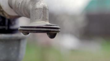 Wasserhahn auf dem Hintergrund der Natur. Das Öffnen oder Schließen eines Wasserhahns, um Wasser zu sparen, weist auf ein Problem mit Wassermangel hin. Rustikaler Brunnen mit Tageslicht. selektiver Fokus mit unscharfem Hintergrund. video