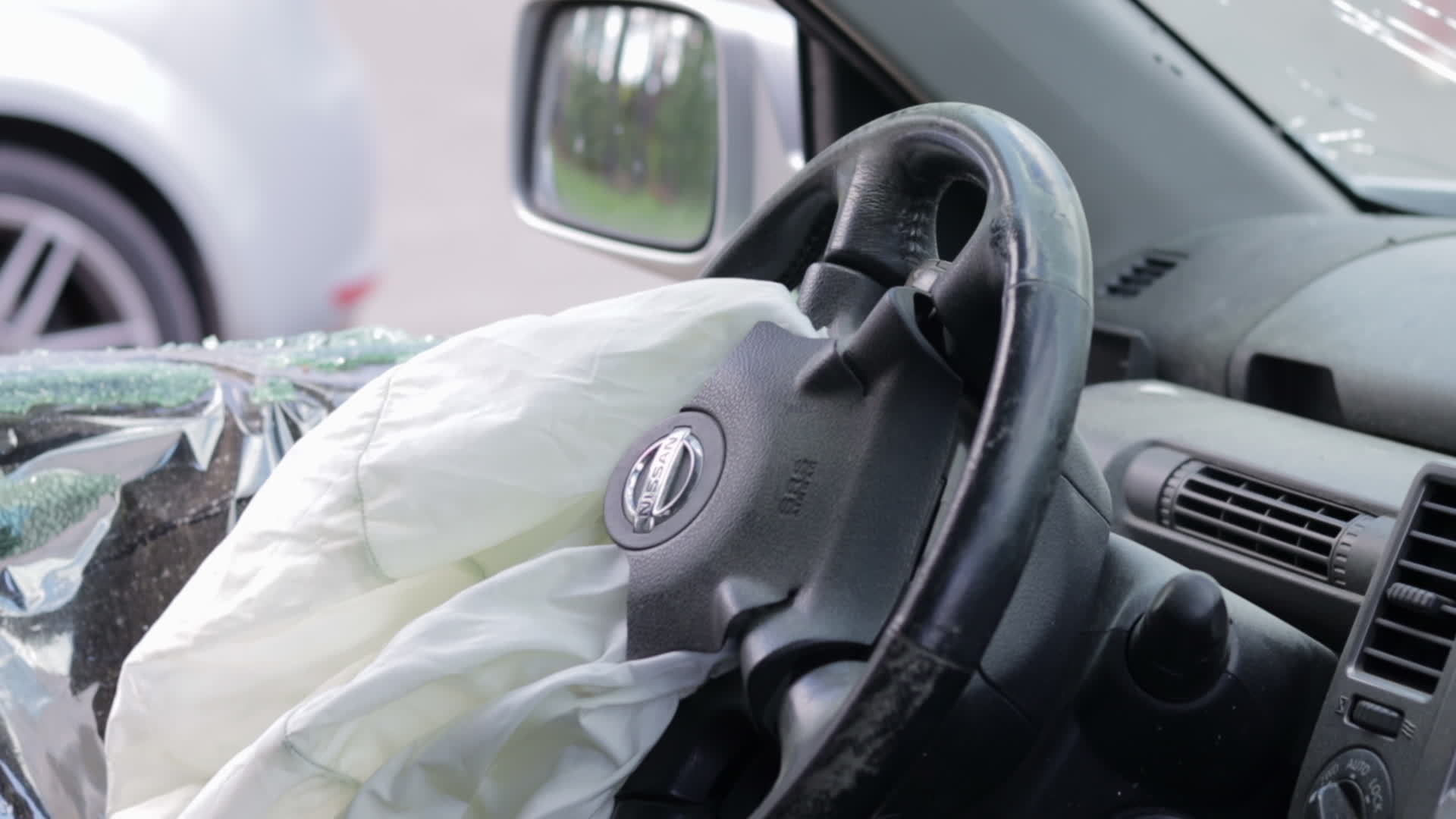 Focus on the steering wheel of the car and the deployed airbag. Airbag