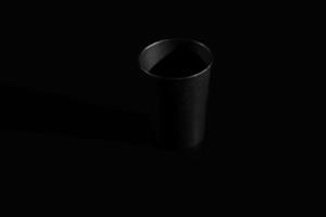 black paper glass isolated on black background. a glass for tea or coffee photo