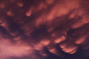 Dramatic sunset landscape with puffy clouds lit by orange setting sun and blue sky. photo