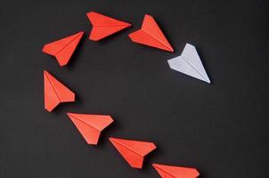 White paper plane origami leading red planes on dark background. Leadership skills concept photo