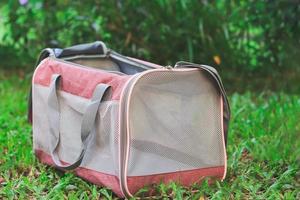 Pet carrier bag  for traveling with pets or visiting veterinarian. Animal transportation bag, on green grass in the garden. photo