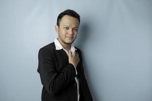 A portrait of a happy attractive Asian man is smiling wearing suit isolated by a blue background photo